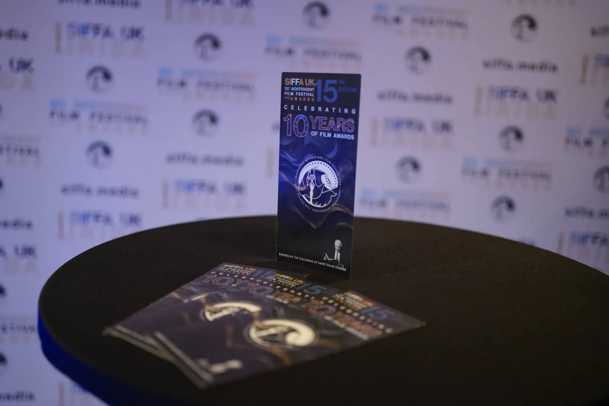 A SIFFA 2025 programme card (15th edition, celebrating 10 years) on a table before the festival backdrop
