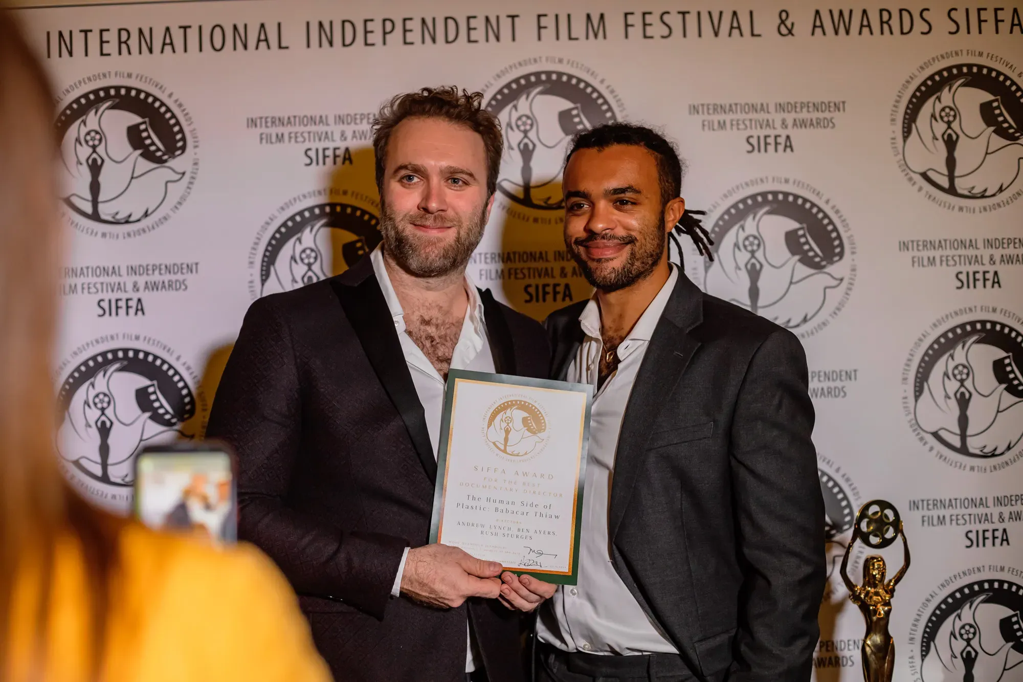 Filmmakers holding their SIFFA award for Best Documentary Director at the 2024 ceremony