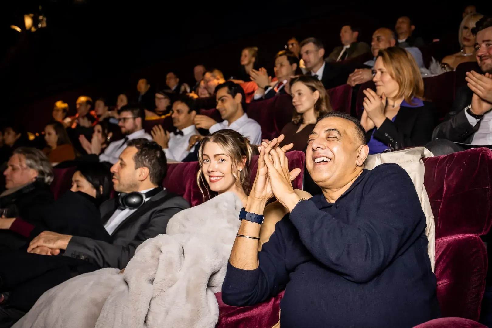 A gala audience applauding in the red-velvet cinema seats