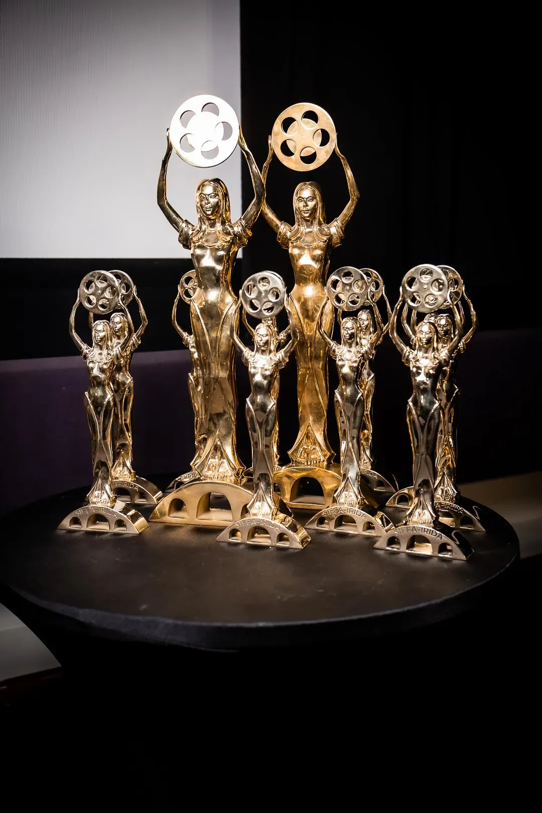 A cluster of gold SIFFA-IRIDA award statuettes, figures holding film reels aloft, arranged on a table
