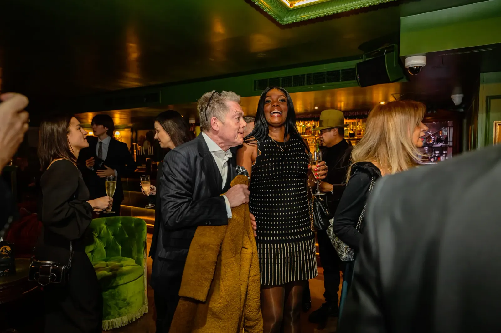 Guests with champagne at the SIFFA 2024 reception, a man in a pinstripe suit greeting a woman in a black-and-gold dress